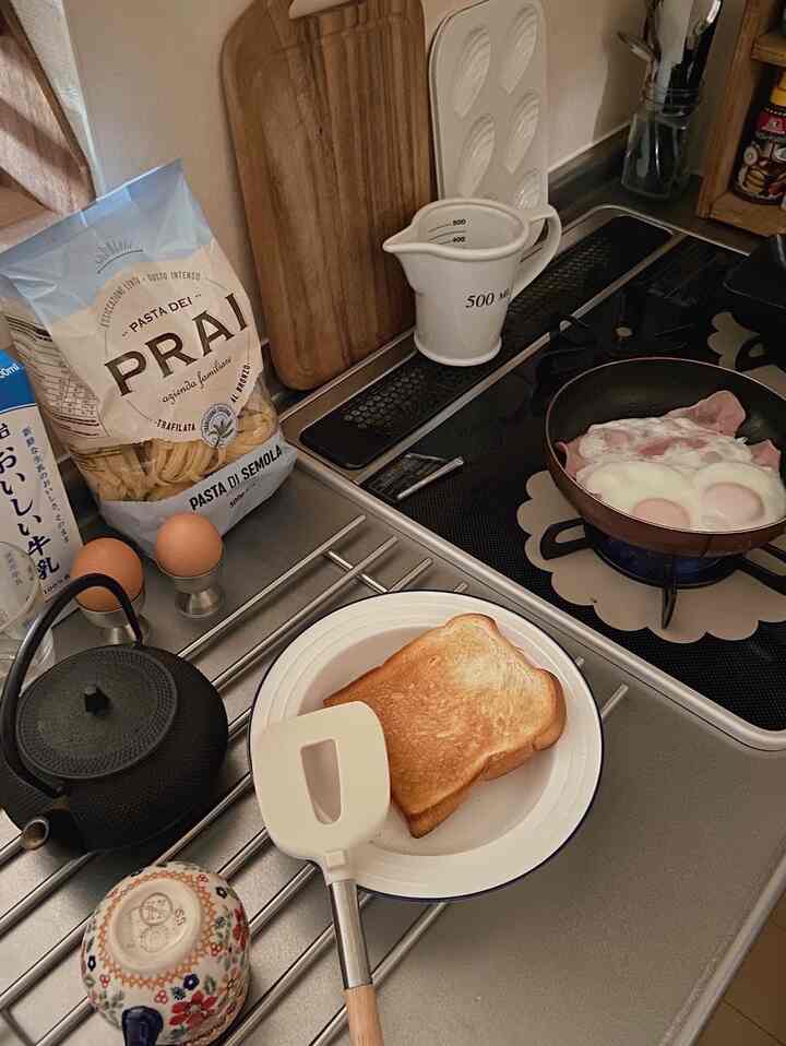 ナチュラルな色調のキッチン、調理器具と朝食が配置された温かみのある雰囲気のインテリア