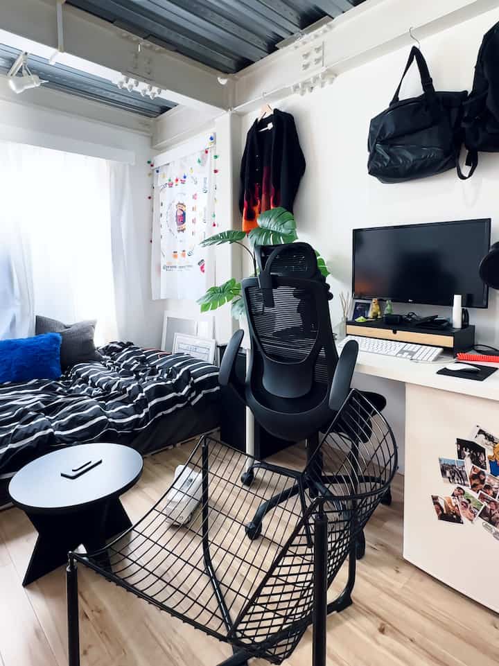 白を基調とした狭いワンルーム、一人暮らし用の実用的なワークスペースとベッドが配置された雰囲気のあるインテリア