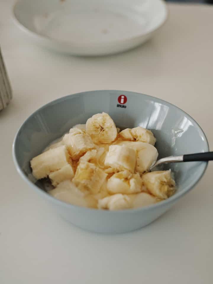 淡いグレーのテーブルに置かれたイッタラのティーマボウルとスライスバナナが入った朝食の風景