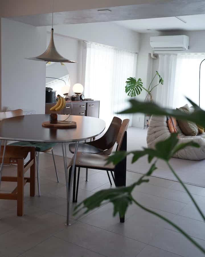 White-toned living and dining space featuring a round dining table, brown furniture, and a modern retro vibe