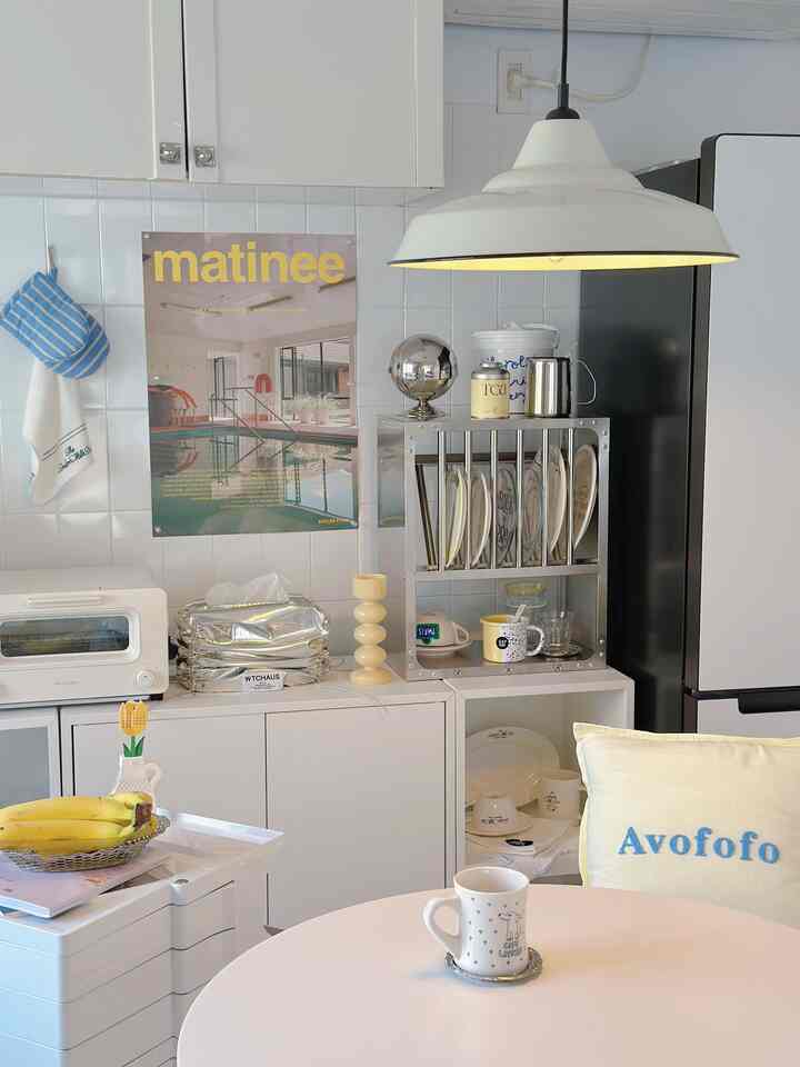 Bright white-toned kitchen featuring a pendant light and stainless steel kitchen rack in a clean, neutral space