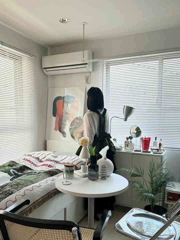 ホワイトトーンの寝室、ベッドと丸テーブル、ブラインドが配置された印象的なミッドセンチュリーモダンの空間