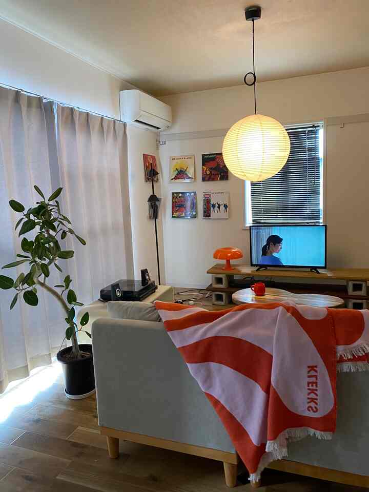 6-tatami living room in white and orange tones featuring a sofa with an orange throw and RICE PAPER SHADE pendant light, creating a cozy atmosphere
