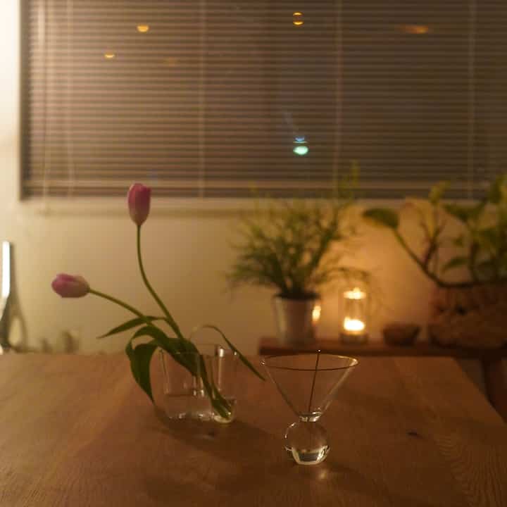 ナチュラルな色調のダイニング、透明な花瓶とオブジェが配置された落ち着いた雰囲気のインテリア