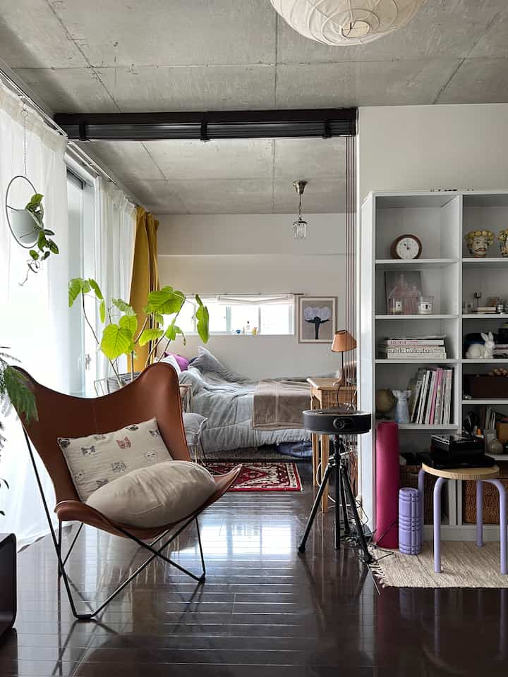Natural and modern bedroom with clear natural light, featuring a bed positioned against the wall and a brown butterfly chair