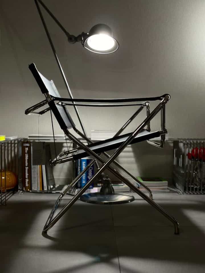 黒とシルバーの色調の狭い部屋に配置されたモダンなアームチェアとフロアランプがある雰囲気の良いインテリア