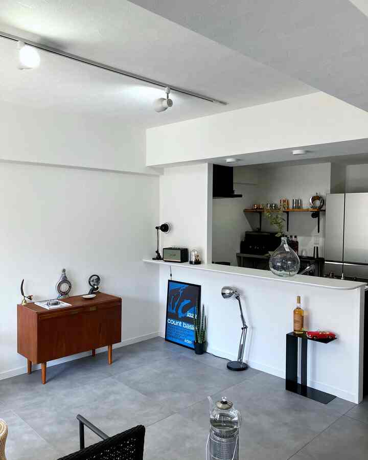 White-tone living room and kitchen featuring a wooden mid-century modern sideboard and simple furniture placement with a clean interior