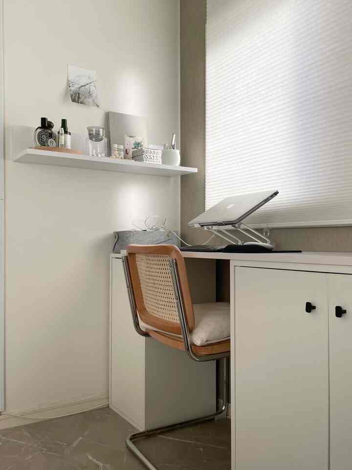 White-toned small home office space featuring a clean storage cabinet and wooden chair in a simple working environment