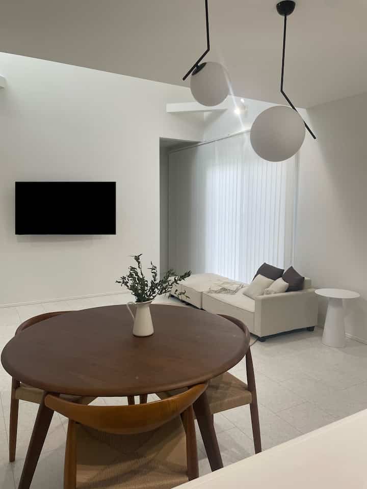 白と木目調が調和した4人用のリビングダイニング、ミニマルで清潔感のある印象的な空間