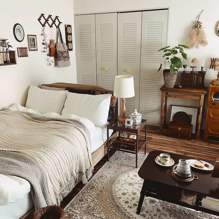 A cozy retro bedroom in white and brown tones featuring antique furniture and a patterned rug