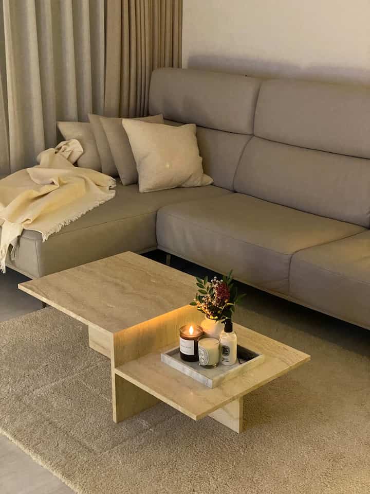 Warm beige-toned living room featuring a large sofa and marble coffee table creating a cozy relaxation space