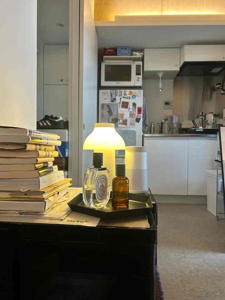 White-toned studio apartment kitchen and living area with tray and table lamp centerpiece in a cozy single household space