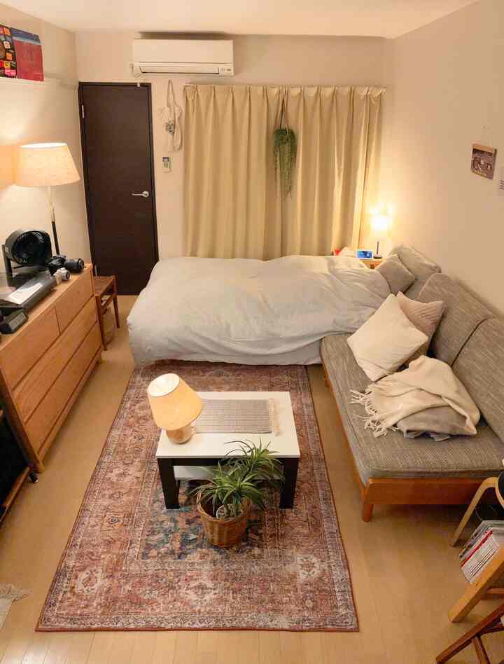 暖かいベージュトーンの1人暮らし用1Kリビング、ナチュラルウッド家具と間接照明が作る雰囲気のあるインテリア