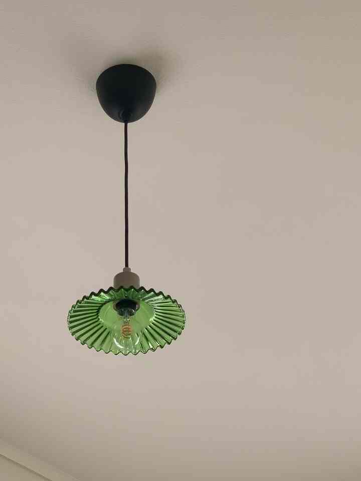 グレートーンの寝室天井に配置されたグリーンのレトロなペンダントライトが印象的な空間