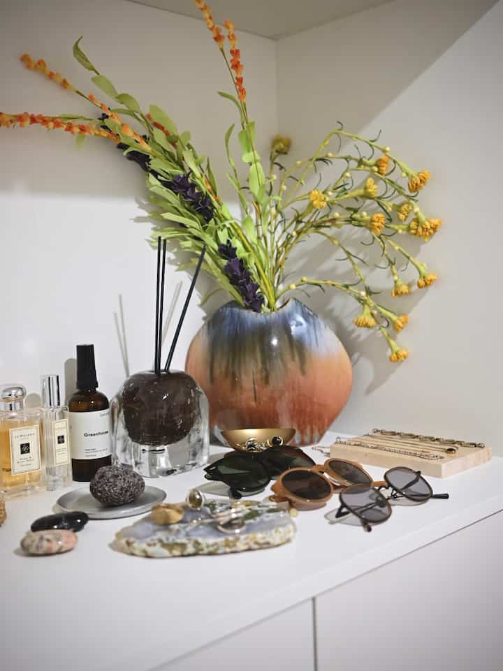 白を基調とした玄関、カラフルな花瓶とアクセサリーが配置された整理された収納スペース