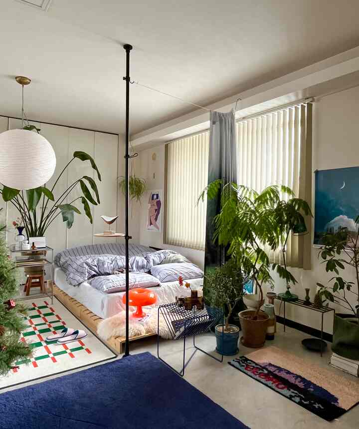 ネイビーとホワイトの色調の寝室、木製ベッドと多様な植物が配置され、雰囲気のあるカフェ風インテリア