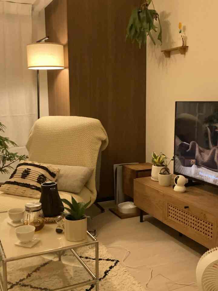 ブラウンとホワイトのトーンが特徴の一人暮らしリビング、フロアランプとコーヒーテーブルが配置された温かみのある空間