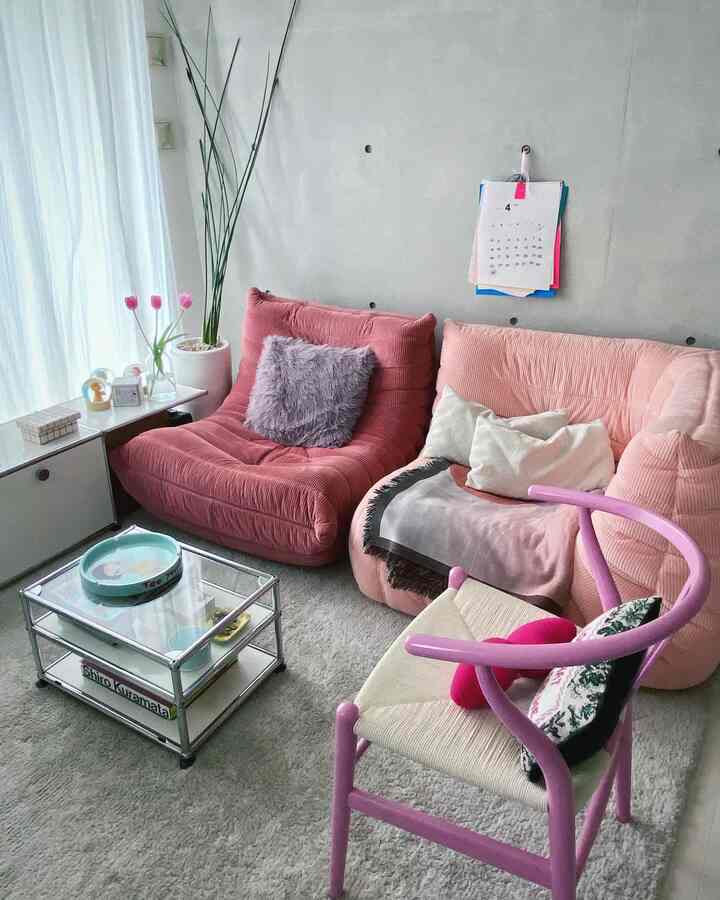 ピンクとナチュラルカラーが調和したリビング、リーンロゼのソファとYチェア、クッションやガラスのコーヒーテーブルが配置された雰囲気のある空間