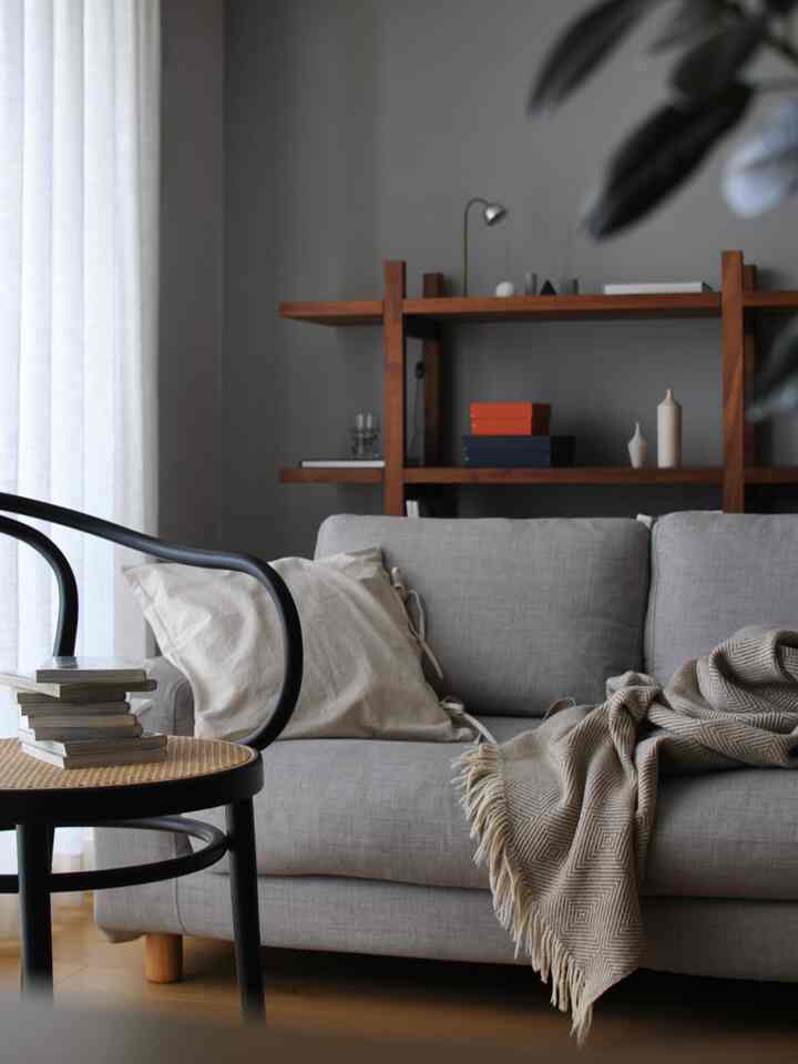 ナチュラルトーンのリビング、グレーのソファと木製の棚が配置された雰囲気のあるインテリア