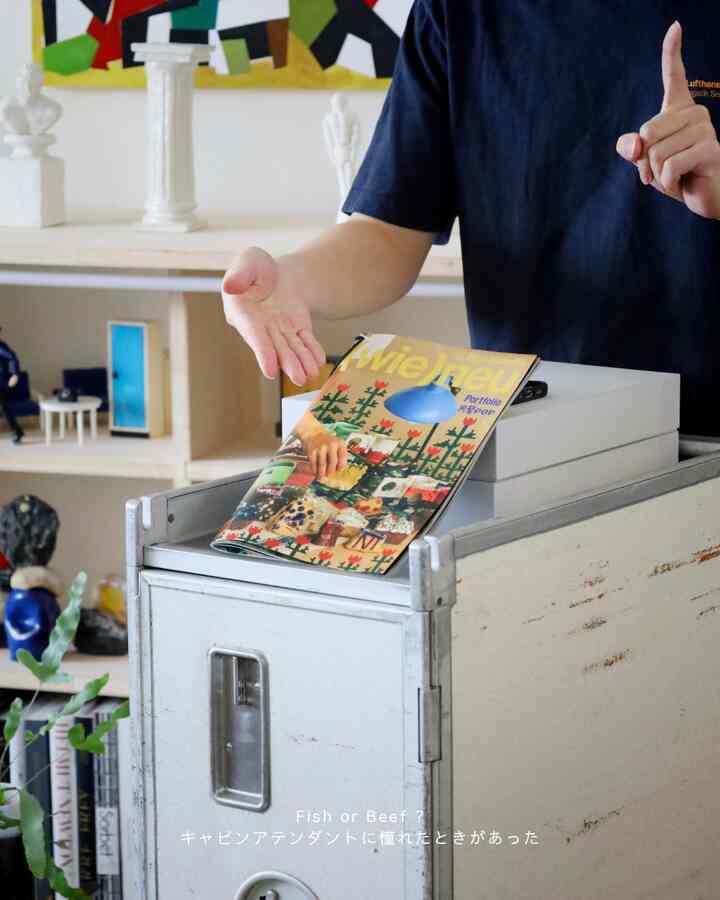 白い壁と家具が背景のミニマルな書斎、抽象的なアート作品と本棚が配置された空間