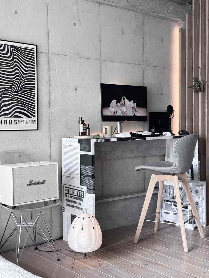 Gray and white dominated industrial style compact home office featuring concrete wall, wooden floor, desk, and chair
