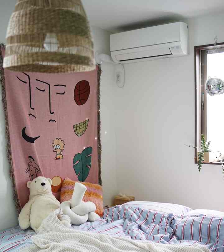 ホワイトとピンクの色調の寝室、かわいいクッションとくまのぬいぐるみが配置された温かみのあるインテリア