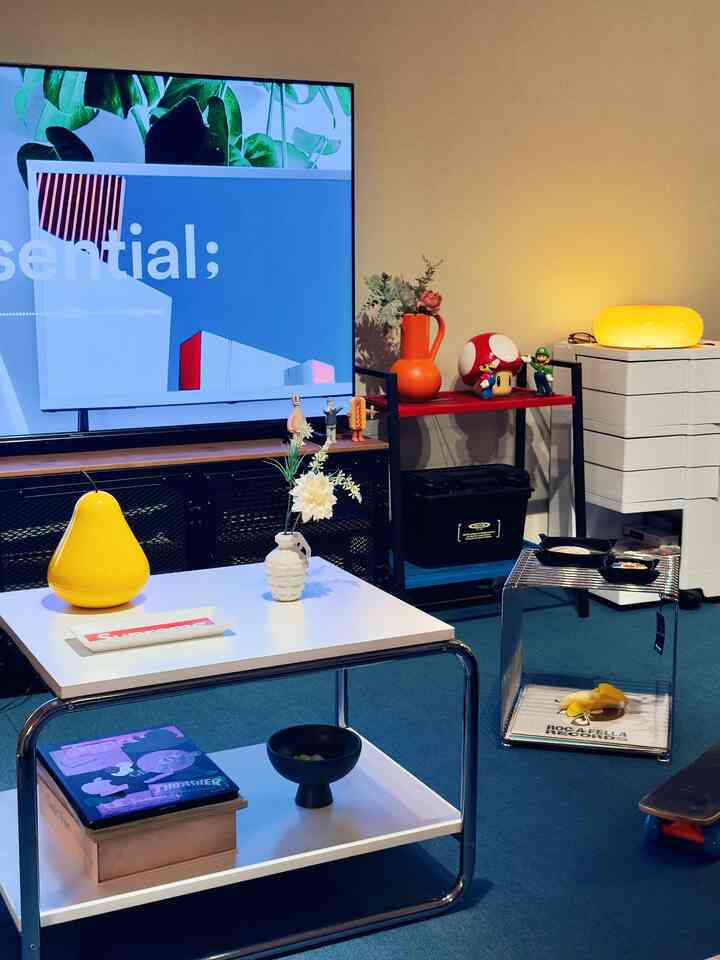 白いテーブルと青いカーペットのあるリビングルーム、棚とテレビ台が配されたモダンでナチュラルな空間