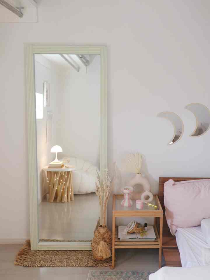 ナチュラルカラーの寝室、大型の鏡と木製のナイトテーブルが配置された雰囲気のある空間