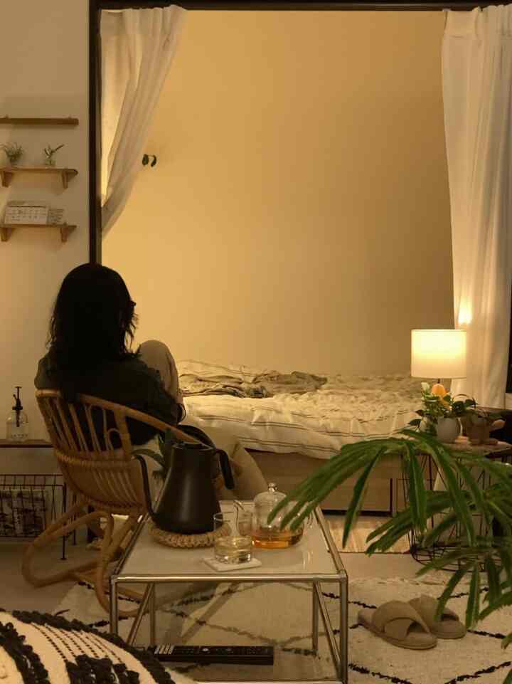 ベージュ色の壁とナチュラルな木製家具が配置された1LDKのリビング兼寝室、落ち着いた雰囲気のある空間