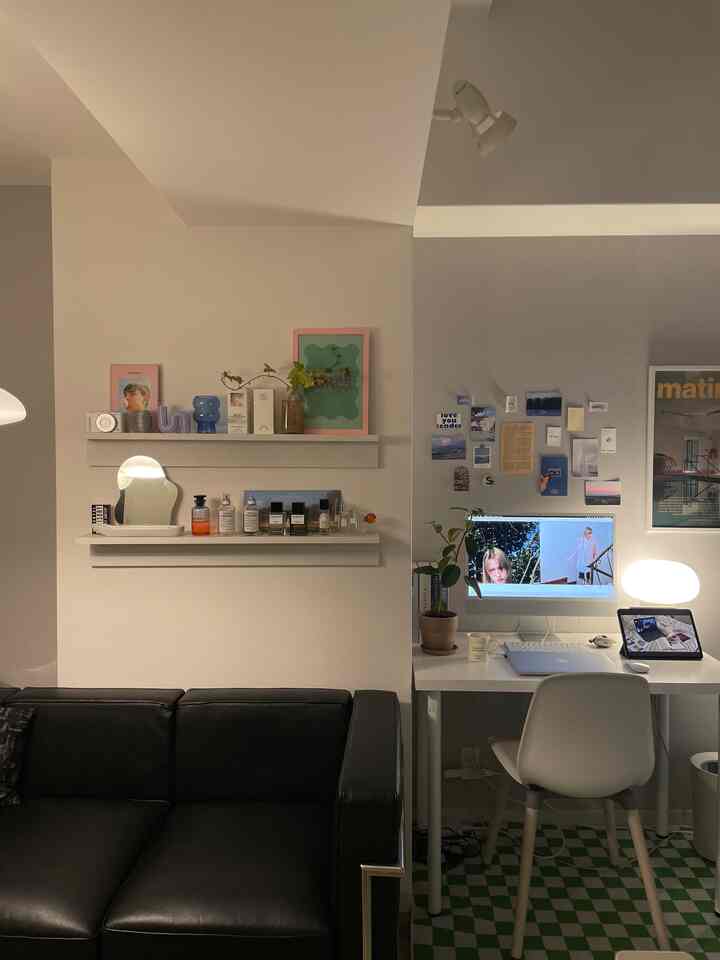 Cozy study space featuring compact white and black toned home office setup with sofa, decorated with plants and artwork