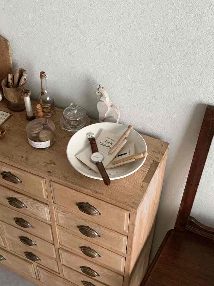 ナチュラルな木目調のチェストとヴィンテージ雑貨が配置された、落ち着いたアンティーク風の部屋の一角