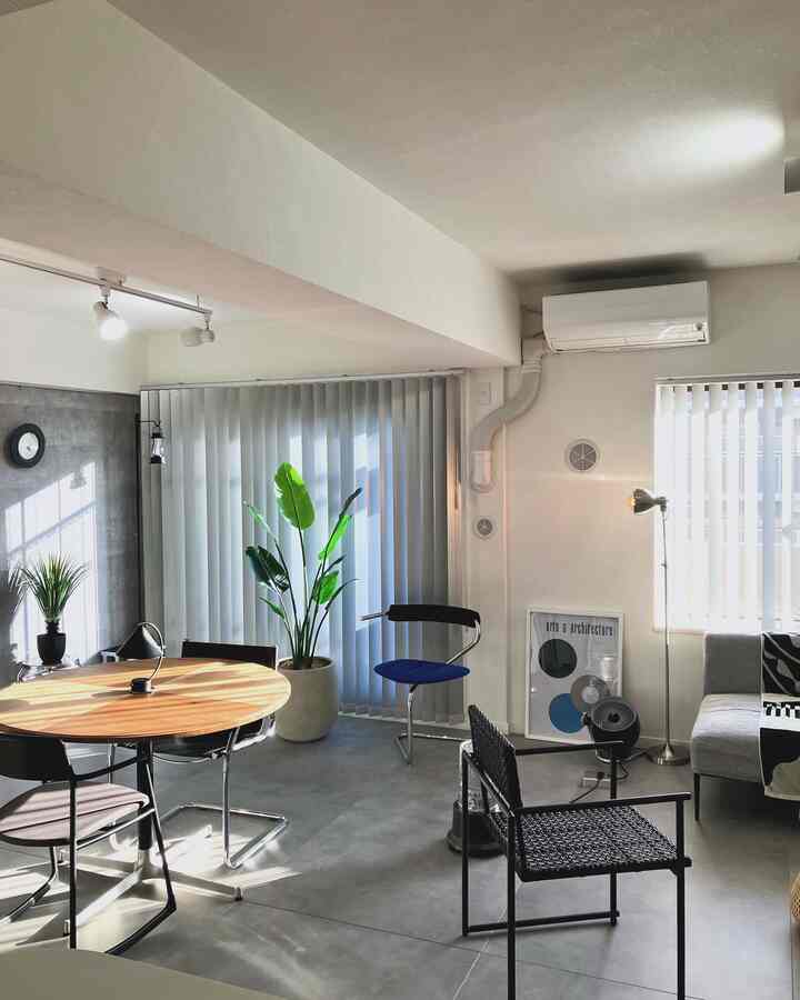 白と木目調が調和したダイニングルーム、シンプルでインダストリアルな家具と大きなグリーンプラントが配置された雰囲気のあるインテリア