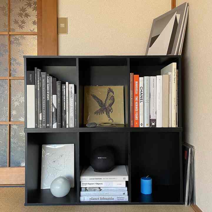 Natural-toned small room corner featuring a black storage box filled with books and decor