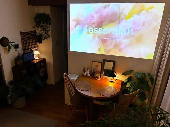 Wood tone dining room featuring a round dining table, indirect lighting, and a cozy atmosphere with a projector screen on the wall