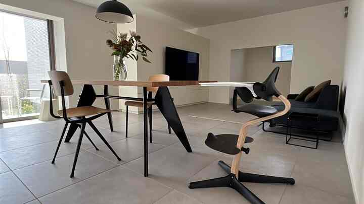 白い壁と木目調のテーブルが配されたモダンな2人暮らしのリビング、黒い家具とペンダントライトが調和する印象的な空間