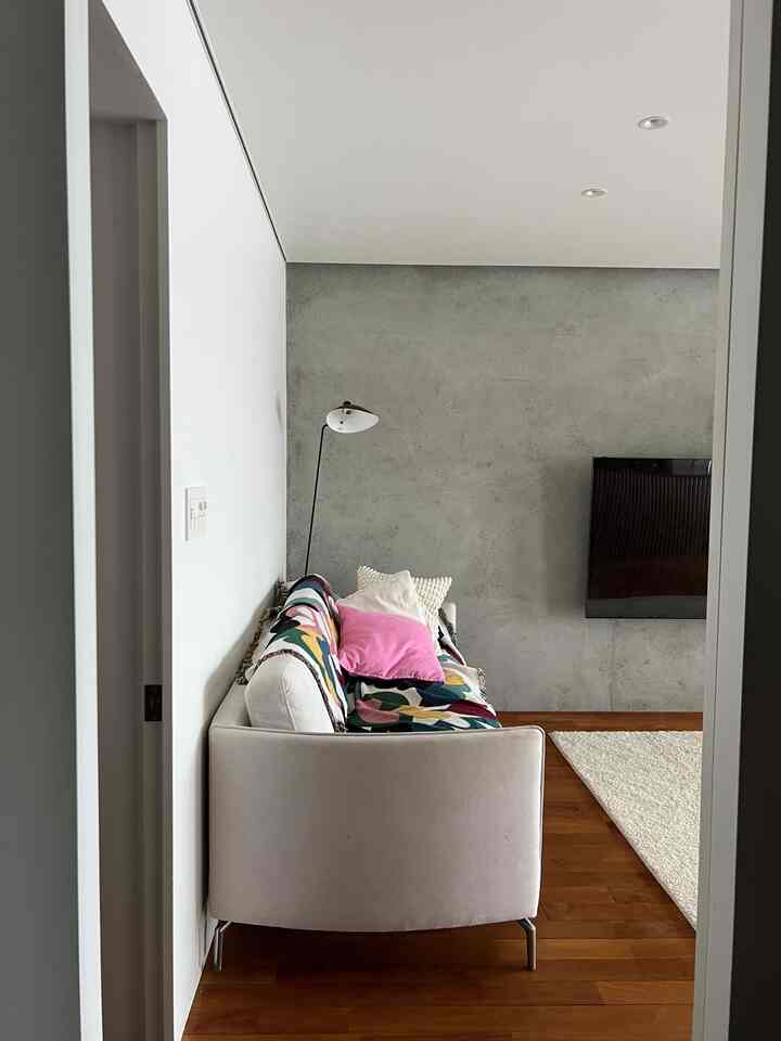 Modern living room with white walls and wood tone flooring, featuring a white sofa and floor lamp in a calm setting