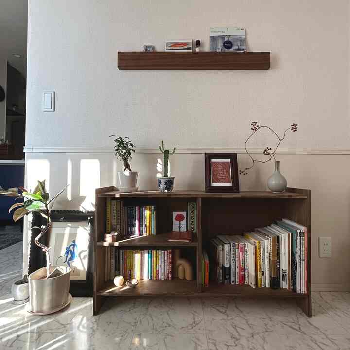 ナチュラルトーンのリビング、レトロな本棚と棚が配置され、多数の植物が温かみのある雰囲気を演出しているインテリア