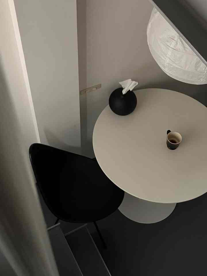 A cozy cafe-style home cafe in a small room featuring a white round table and black armchair in black and white tones