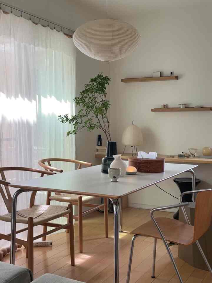 白と自然な色調のダイニングルーム、シンプルなテーブルと木製チェアが配置され、清潔で広々とした印象的な空間