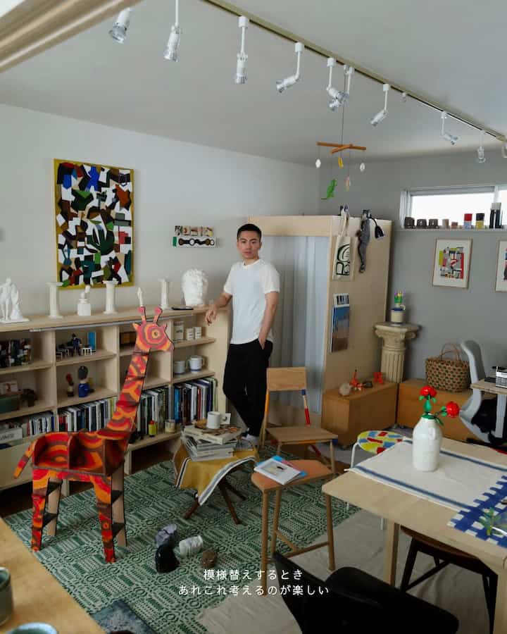 ナチュラルな色調のリビング、書棚や様々な家具、モビールが配置された雰囲気のあるインテリア