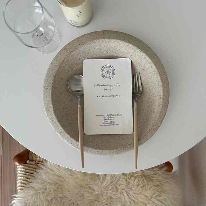 白を基調としたダイニングテーブルにベージュの皿とカトラリーがシンプルに配置された印象的な食卓空間