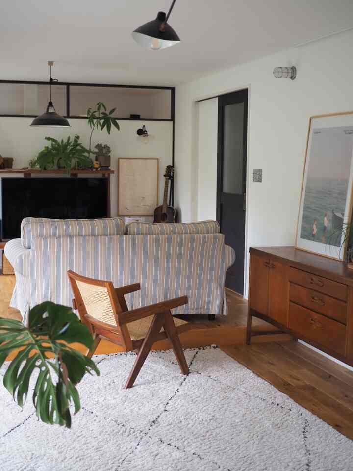 Natural-tone living room featuring wooden furniture, striped sofa, and plants creating a cozy space