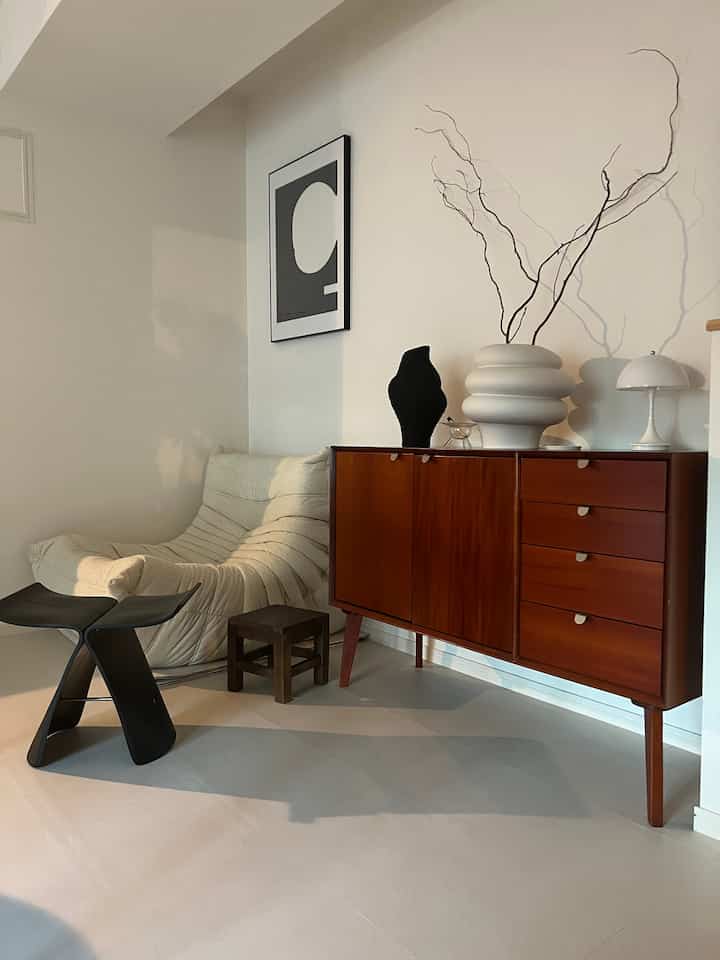 白い壁と北欧風の木製サイドボードが配置されたリビング、自然素材とモダン家具が調和する雰囲気のあるインテリア