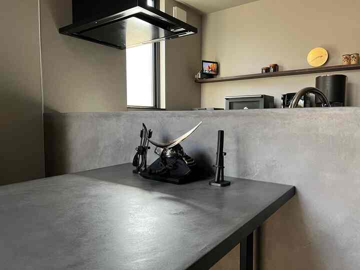 Modern dining room in gray and black tones featuring a Mortex table with traditional black samurai armor display