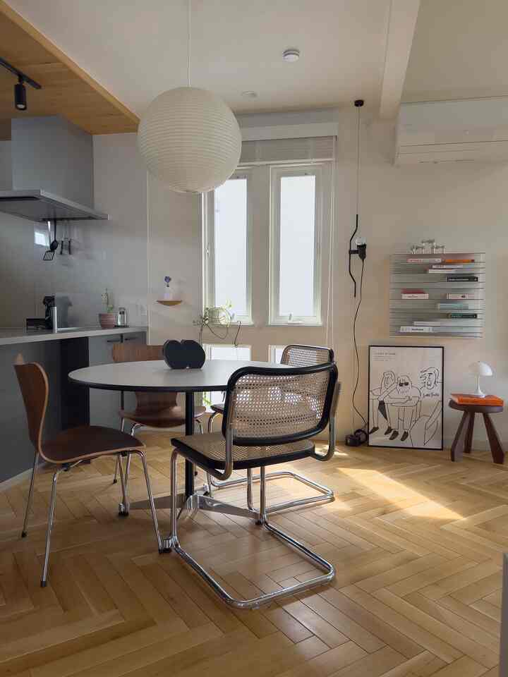 Bright white and wood tone dining room featuring round table, mixed chairs, pendant light creating a modern natural vibe