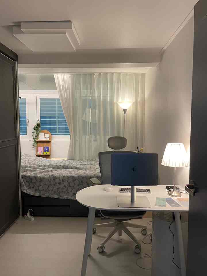 White and gray toned single household bedroom combined with home office, featuring simple modern desk and office chair