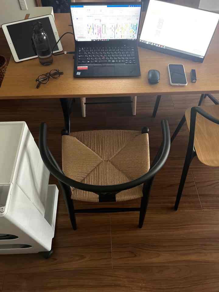 Wood tone and black harmonize in a modern home office space featuring a compact wooden desk with laptop, monitors, and Wishbone chair