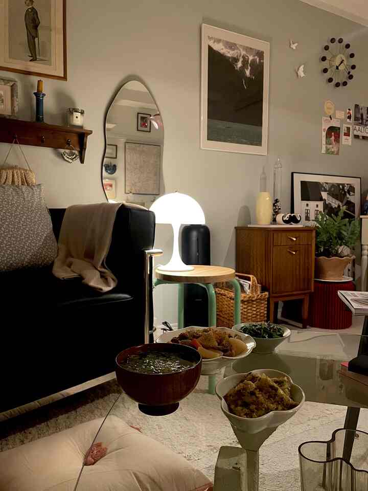 Living room with black sofa, natural wood-toned furniture, and warm lighting creating cozy ambiance