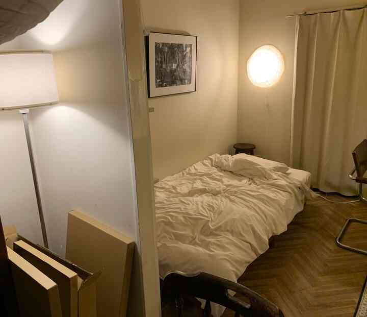 白と木目調の寝室、シンプルな家具と暖かい照明が配置された落ち着いた空間