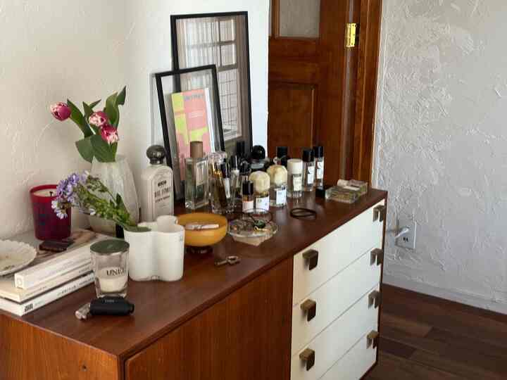 ウッドトーンとホワイトのナチュラルなキャビネット空間、香水や小物が調和するヴィンテージな雰囲気のインテリア